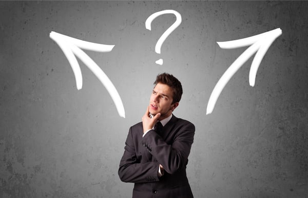 Young businessman taking a decision with arrows and question mark above his head