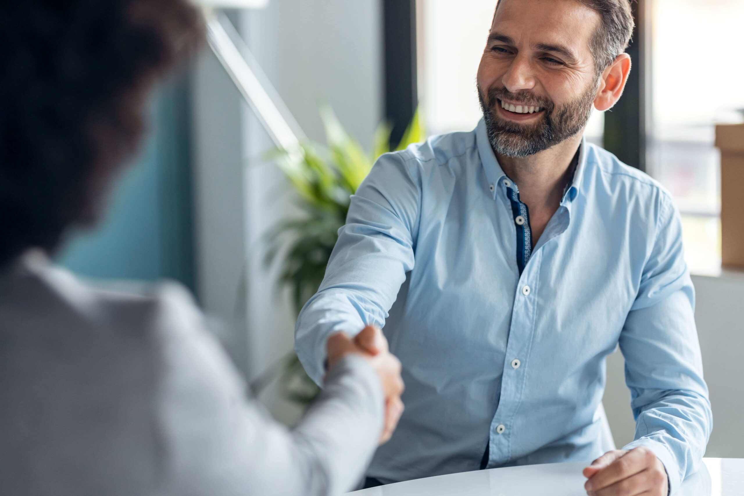 Attractive real estate agent shaking hands with yo