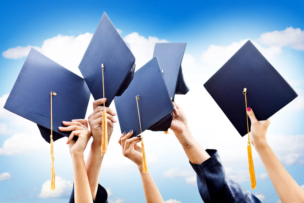 Unrecognizable group of people throwing graduation hats in the air