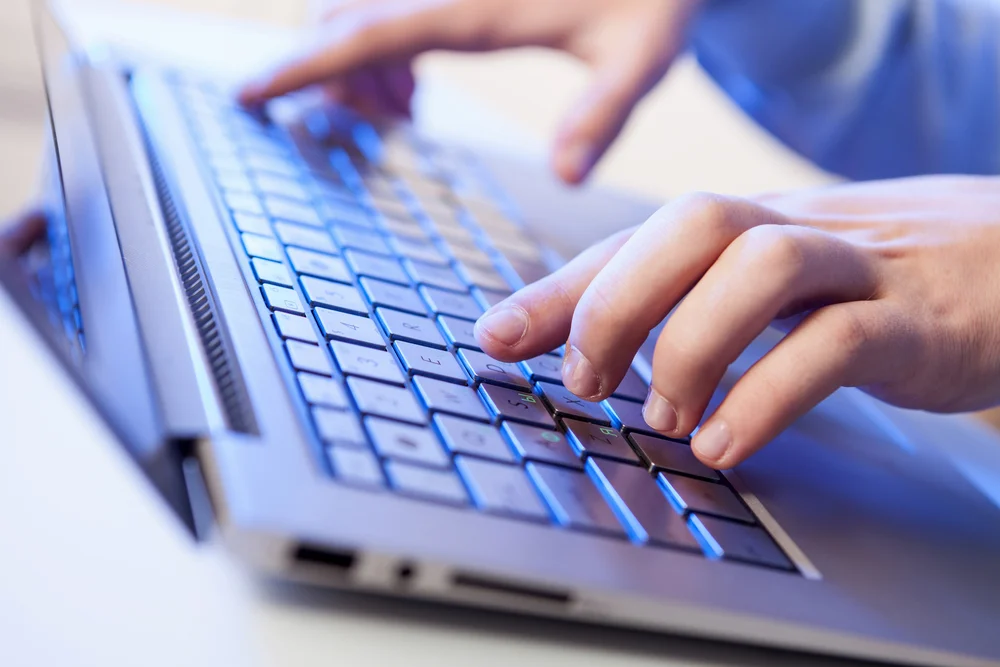Сlick hands of a man on a keyboard with blue backlighting
